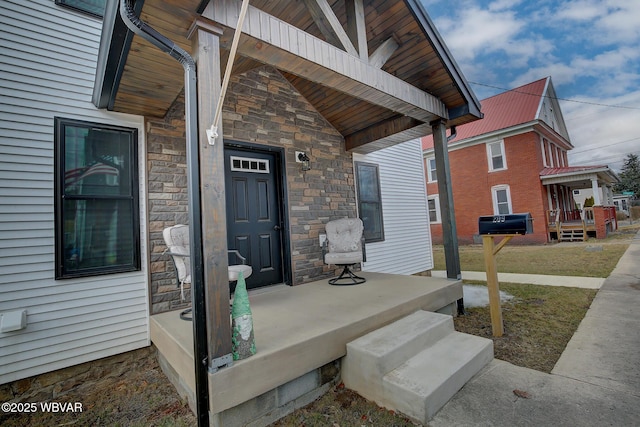 property entrance featuring covered porch, stone siding, and metal roof