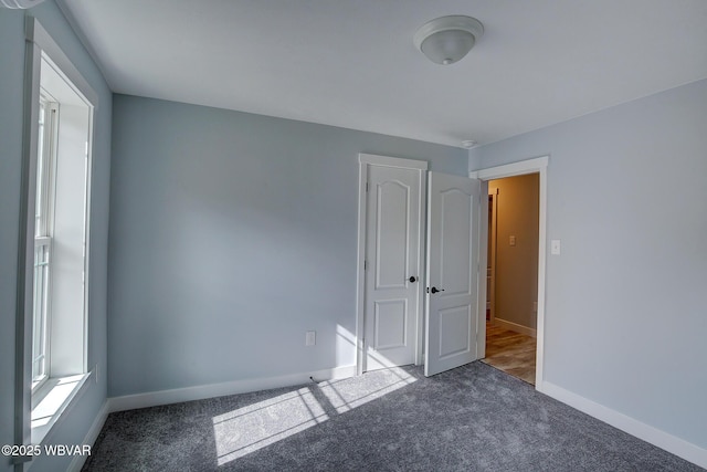 spare room featuring carpet and baseboards