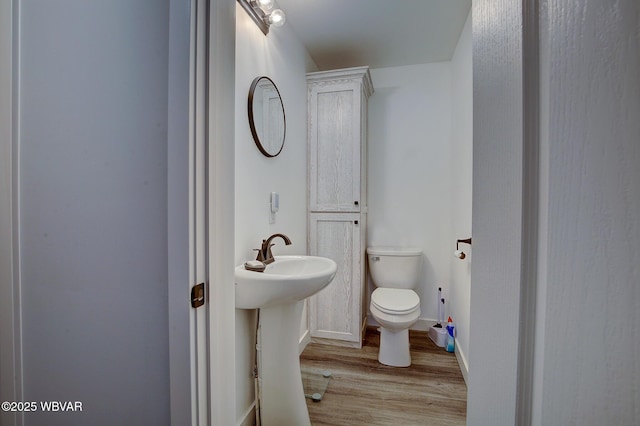 bathroom with baseboards, a sink, toilet, and wood finished floors