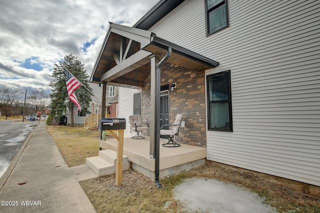 property entrance featuring stone siding and a porch