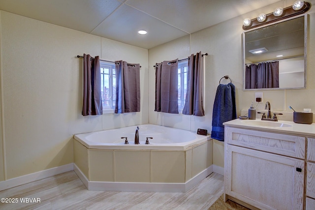 bathroom featuring vanity, baseboards, and a bath