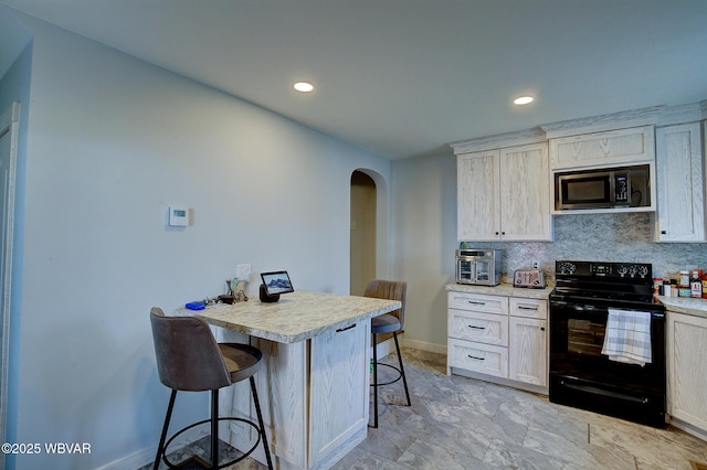 kitchen featuring arched walkways, a breakfast bar, tasteful backsplash, stainless steel microwave, and electric range