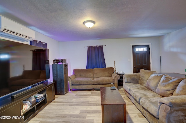 living room featuring a textured ceiling, light wood finished floors, and a wall mounted air conditioner