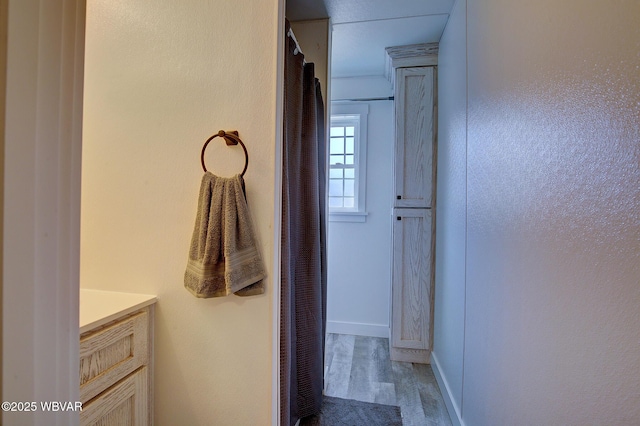 bathroom featuring baseboards, wood finished floors, and vanity