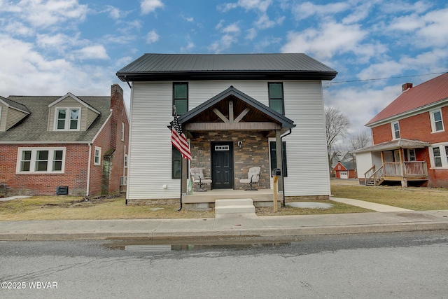 view of front of house with a porch, stone siding, metal roof, and a front lawn