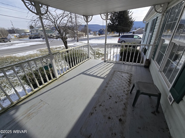 snow covered back of property with a mountain view and a porch