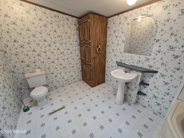 bathroom featuring toilet, ornamental molding, and a textured ceiling