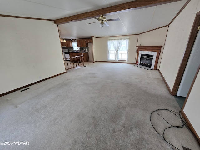 unfurnished living room featuring light carpet, a tile fireplace, lofted ceiling with beams, and ceiling fan