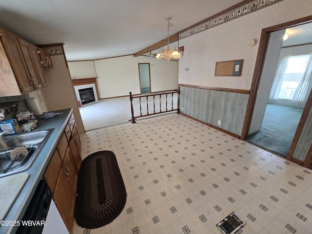 kitchen with hanging light fixtures, sink, a tiled fireplace, wood walls, and beamed ceiling