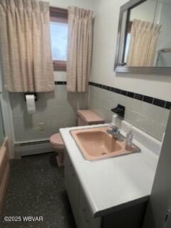 full bathroom with toilet, shower / bath combination with glass door, tile walls, baseboard heating, and vanity