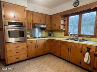 kitchen with black electric stovetop, sink, ventilation hood, and oven