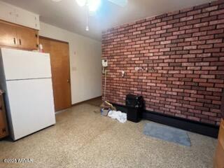 unfurnished living room featuring brick wall