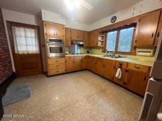 kitchen featuring ceiling fan, stainless steel oven, brick wall, and sink