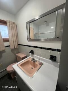 bathroom with vanity, decorative backsplash, baseboard heating, and toilet