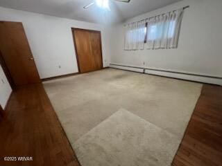 unfurnished bedroom with dark hardwood / wood-style flooring, a baseboard radiator, a closet, and ceiling fan