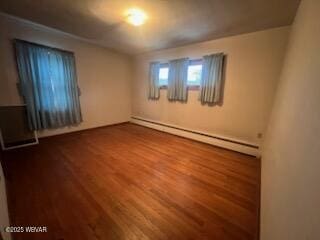 empty room featuring a baseboard radiator and hardwood / wood-style floors