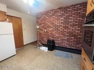 unfurnished living room featuring ceiling fan and brick wall