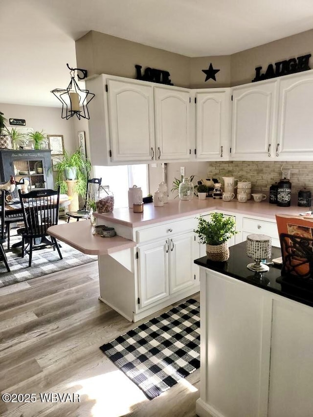 kitchen featuring light countertops, backsplash, light wood-style flooring, and white cabinets