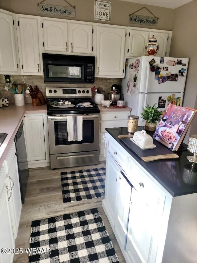 kitchen with black appliances, backsplash, white cabinetry, and light wood-style floors