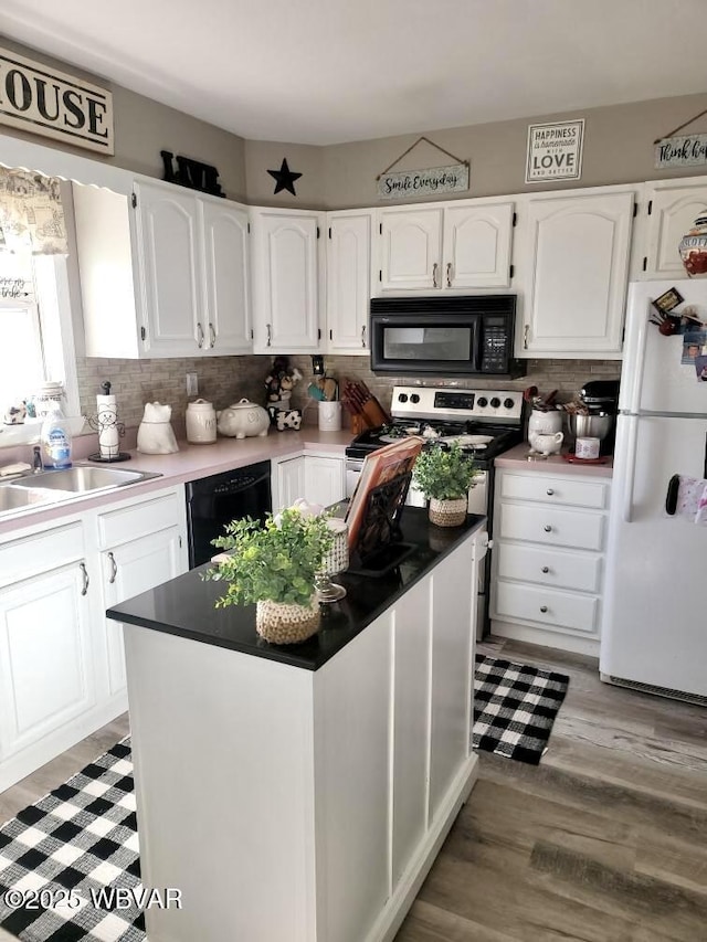 kitchen with tasteful backsplash, white cabinetry, a sink, and black appliances