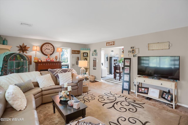 living room with light carpet, visible vents, and baseboards