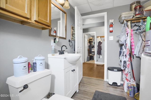 bathroom featuring toilet, a drop ceiling, wood finished floors, and vanity