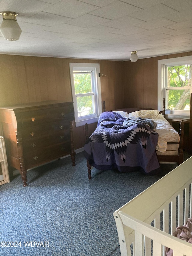 bedroom with carpet floors and wood walls