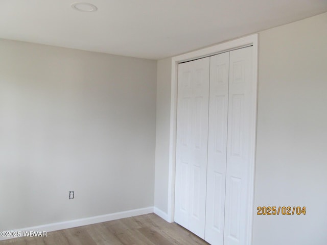 unfurnished bedroom with a closet, light wood-type flooring, and baseboards