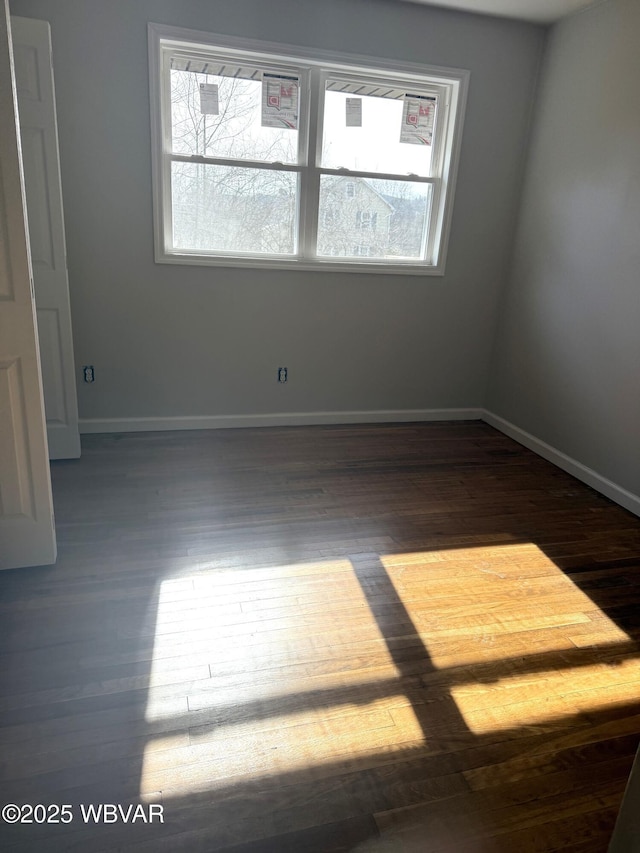 spare room with baseboards and wood finished floors