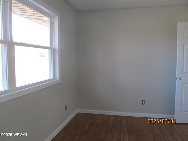 spare room featuring baseboards, dark wood-style flooring, and a healthy amount of sunlight