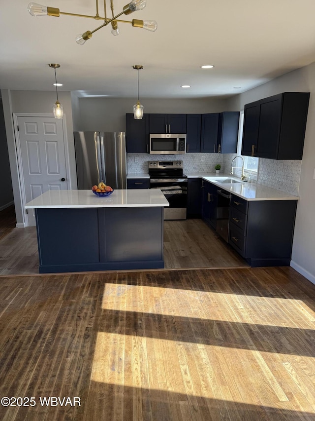 kitchen with a center island, decorative light fixtures, stainless steel appliances, light countertops, and a sink