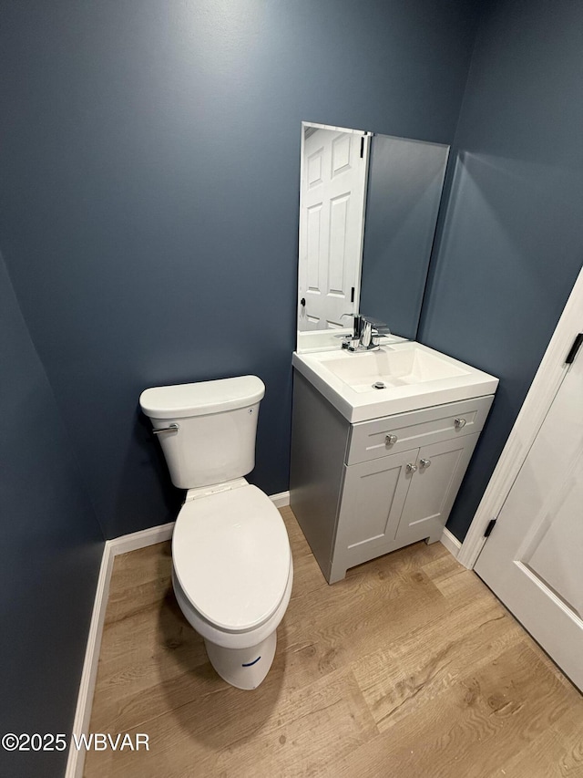 bathroom with wood finished floors, vanity, toilet, and baseboards