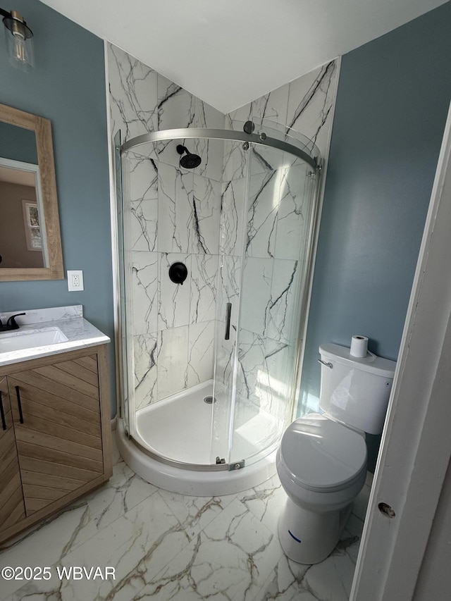 bathroom featuring marble finish floor, vanity, a shower stall, and toilet