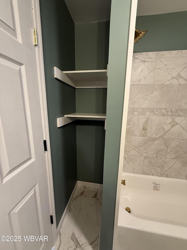 bathroom featuring a tub to relax in, marble finish floor, and baseboards