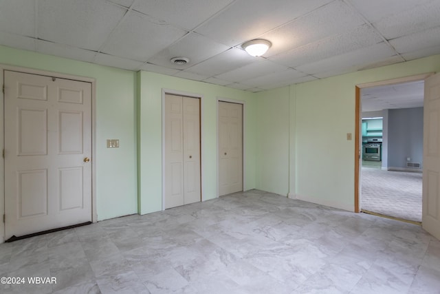 unfurnished bedroom featuring multiple closets and a paneled ceiling