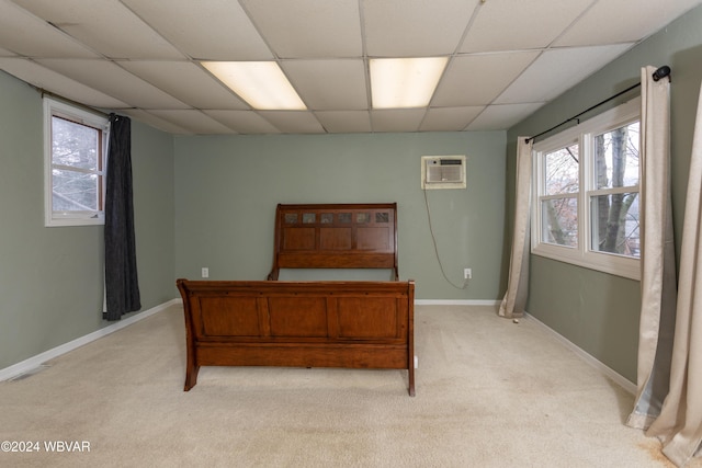 bedroom featuring a paneled ceiling, light colored carpet, and a wall mounted AC