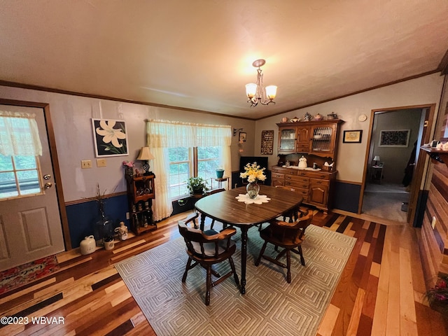 dining room featuring ornamental molding, light hardwood / wood-style floors, vaulted ceiling, and a notable chandelier