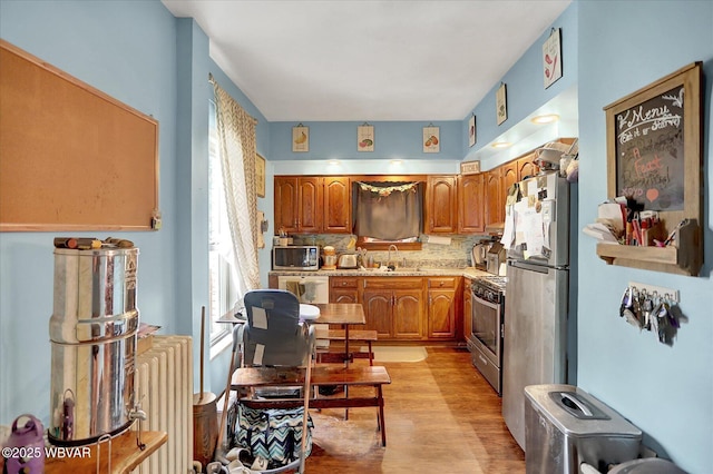 679 2nd Ave, Williamsport, PA 17701 - kitchen with appliances with stainless steel finishes, light wood finished floors, radiator heating unit, and brown cabinetry