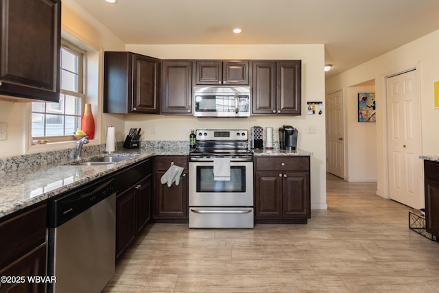 kitchen featuring light stone countertops, dark brown cabinets, stainless steel appliances, and sink