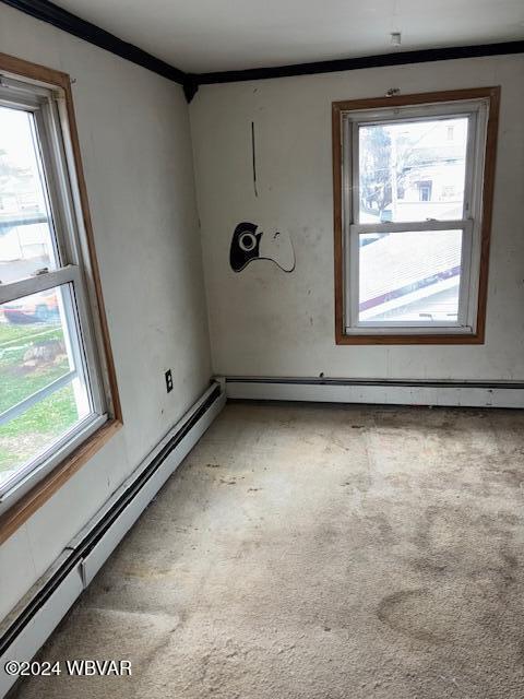 empty room with a baseboard radiator, a wealth of natural light, and crown molding