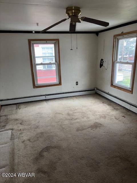 carpeted spare room featuring a baseboard radiator and ceiling fan