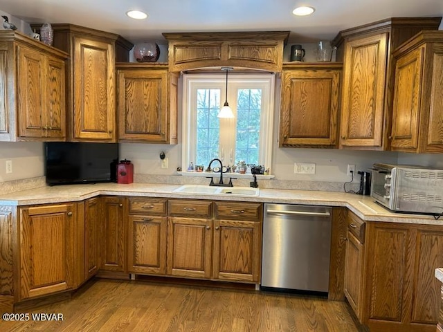 kitchen with stainless steel dishwasher, wood-type flooring, decorative light fixtures, and sink