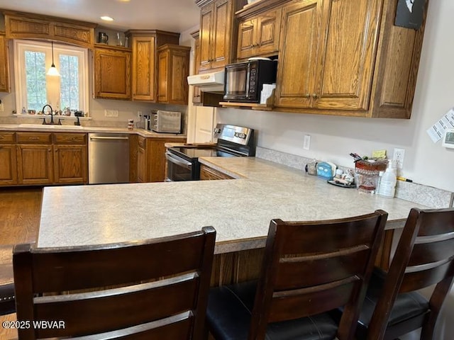 kitchen featuring pendant lighting, sink, a breakfast bar area, and appliances with stainless steel finishes