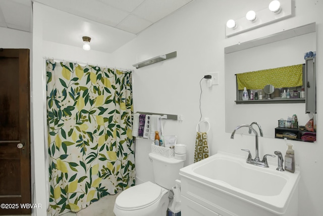 bathroom featuring a shower with curtain, sink, a drop ceiling, and toilet