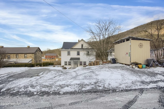 snow covered rear of property with a storage shed