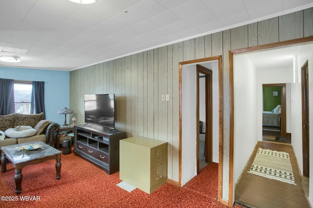 living room featuring crown molding, carpet flooring, and wooden walls