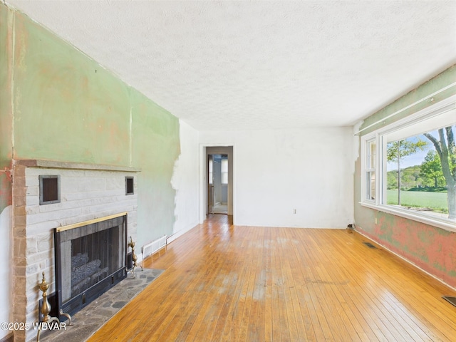 5667 Austinville Rd, Columbia Crossroads, PA 16914 - unfurnished living room featuring a textured ceiling, hardwood / wood-style flooring, a fireplace, and baseboards