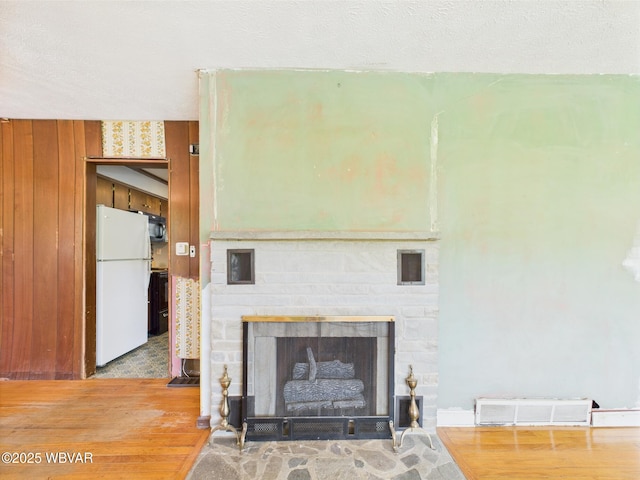 5667 Austinville Rd, Columbia Crossroads, PA 16914 - detailed view of freestanding refrigerator, wood finished floors, a fireplace with flush hearth, black microwave, and range