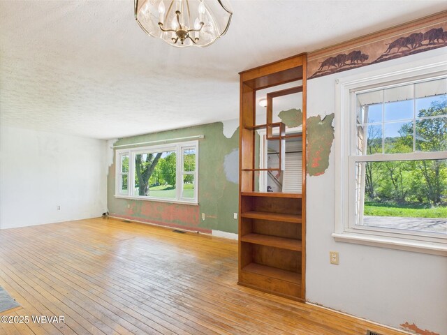 5667 Austinville Rd, Columbia Crossroads, PA 16914 - unfurnished living room featuring healthy amount of natural light, wood-type flooring, a chandelier, and a textured ceiling