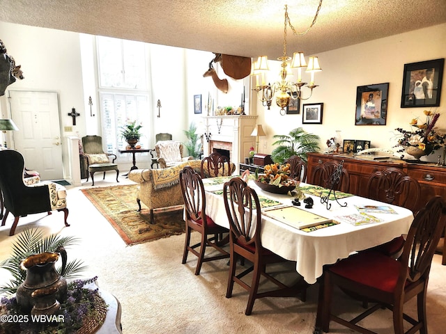 dining area with carpet flooring, a chandelier, a fireplace, and a textured ceiling